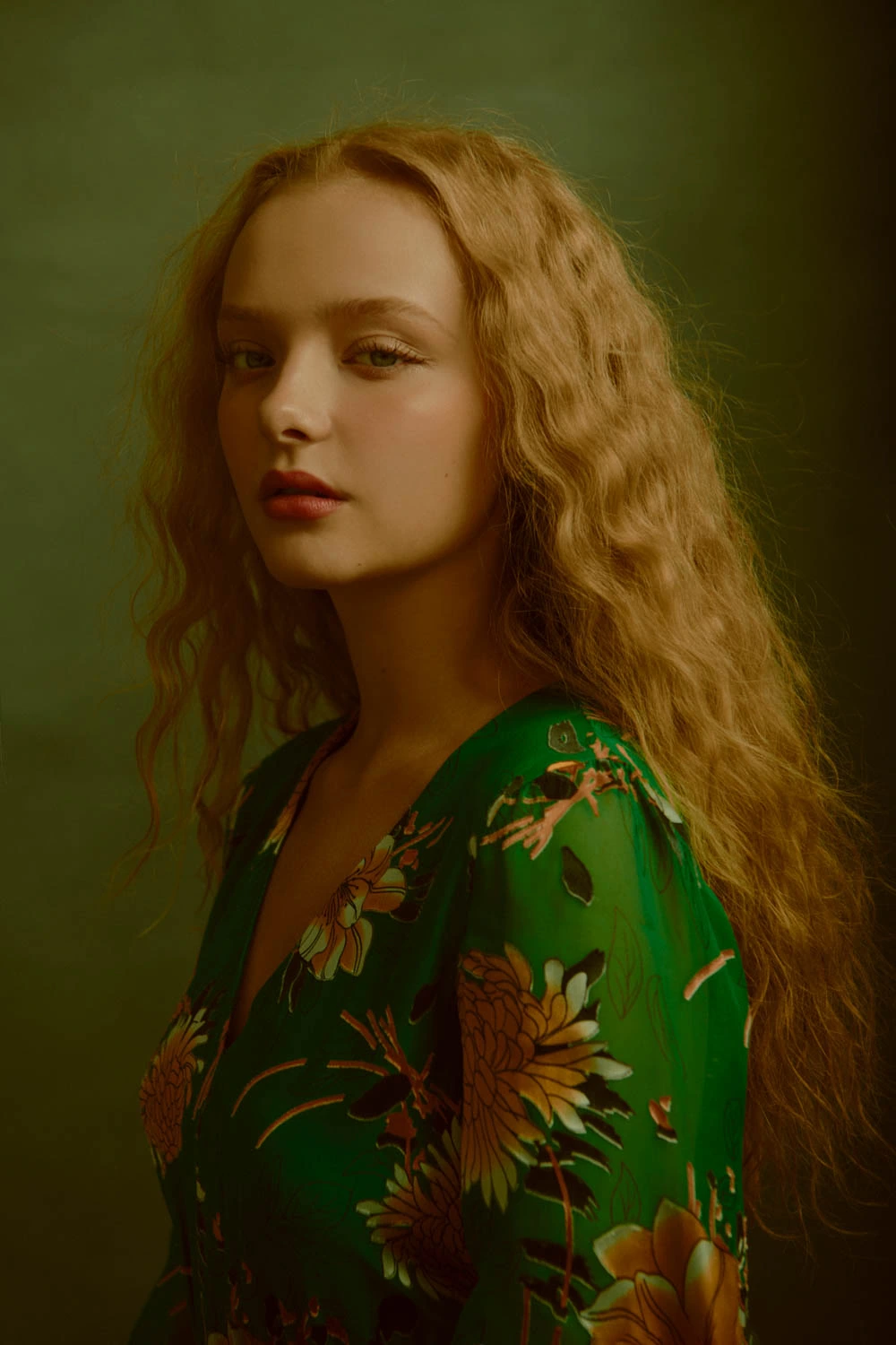 Actress Amiah Miller, star of War for the Planet of the Apes, in a green floral dress, long auburn waves, warm studio light.