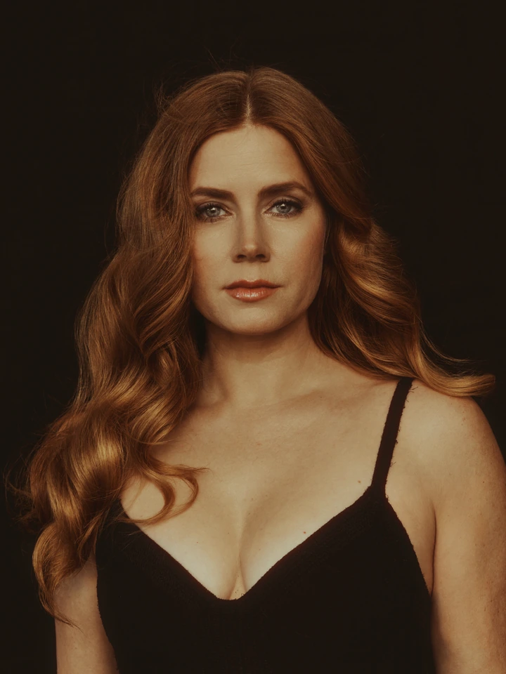 Actress Amy Adams, two-time Golden Globe winner, steady gaze in a black dress, warm amber light against deep shadow, for The.
