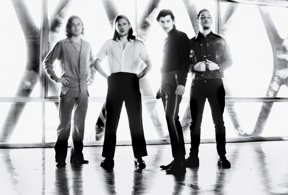 Arctic Monkeys — four members in sharp black-and-white, standing cool before blinding glass and steel, dark tailored looks.