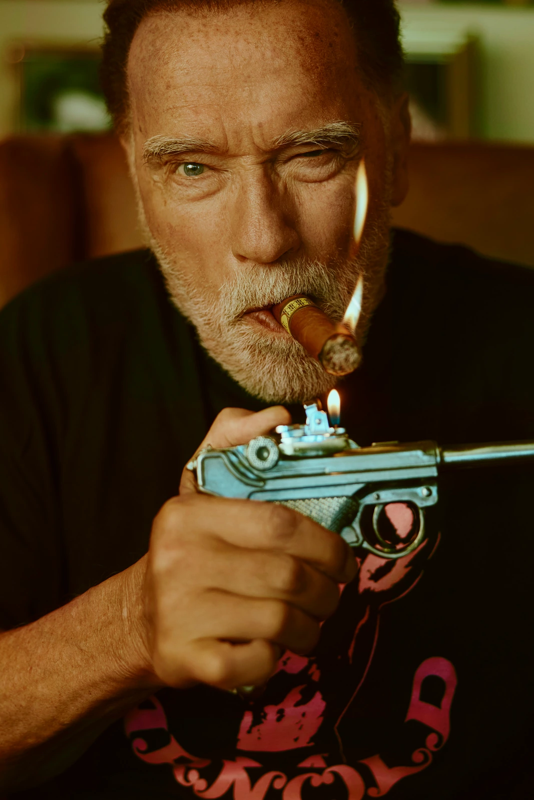 Actor Arnold Schwarzenegger lighting a cigar with a pistol-shaped lighter, intense gaze under warm amber light.