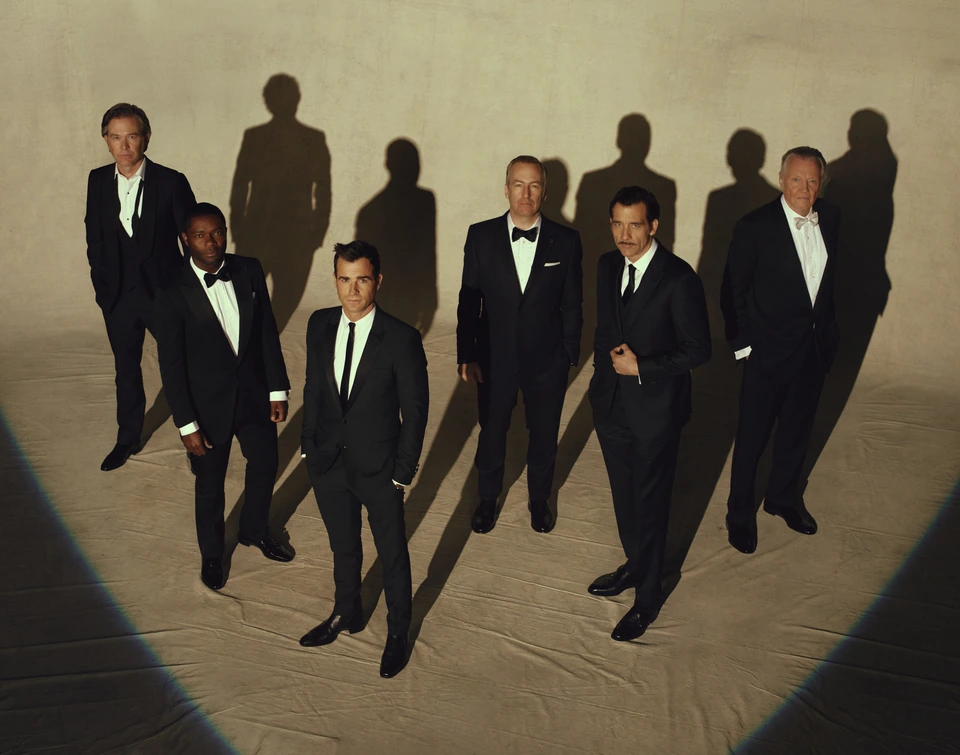 Actors Tim Hutton, David Oyelowo, Justin Theroux, Bob Odenkirk, Clive Owen, Jon Voight in tuxedos under a warm spotlight.