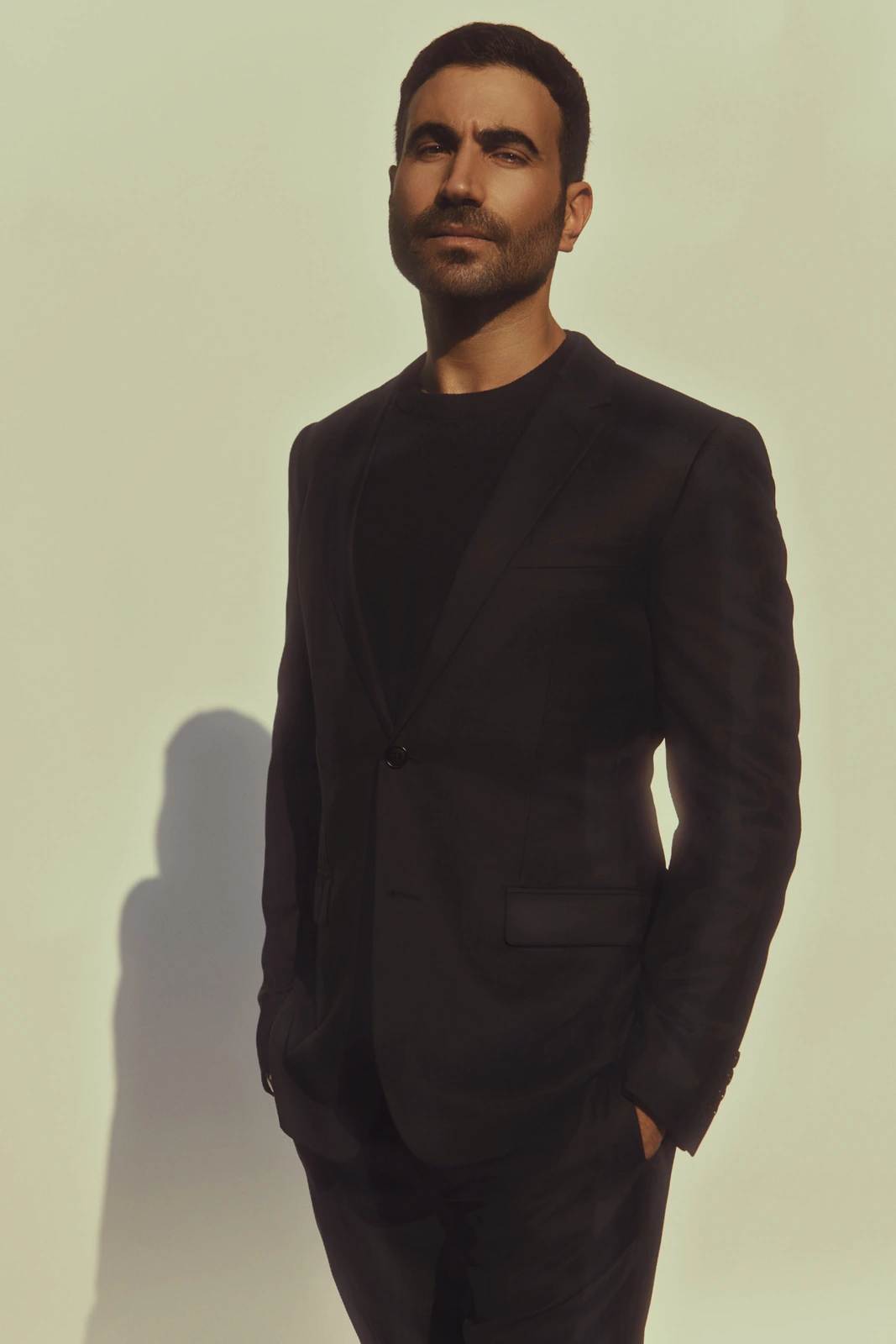 Actor Brett Goldstein, two-time Emmy winner, in a black blazer and crewneck, hands in pockets, warm light casting a soft.