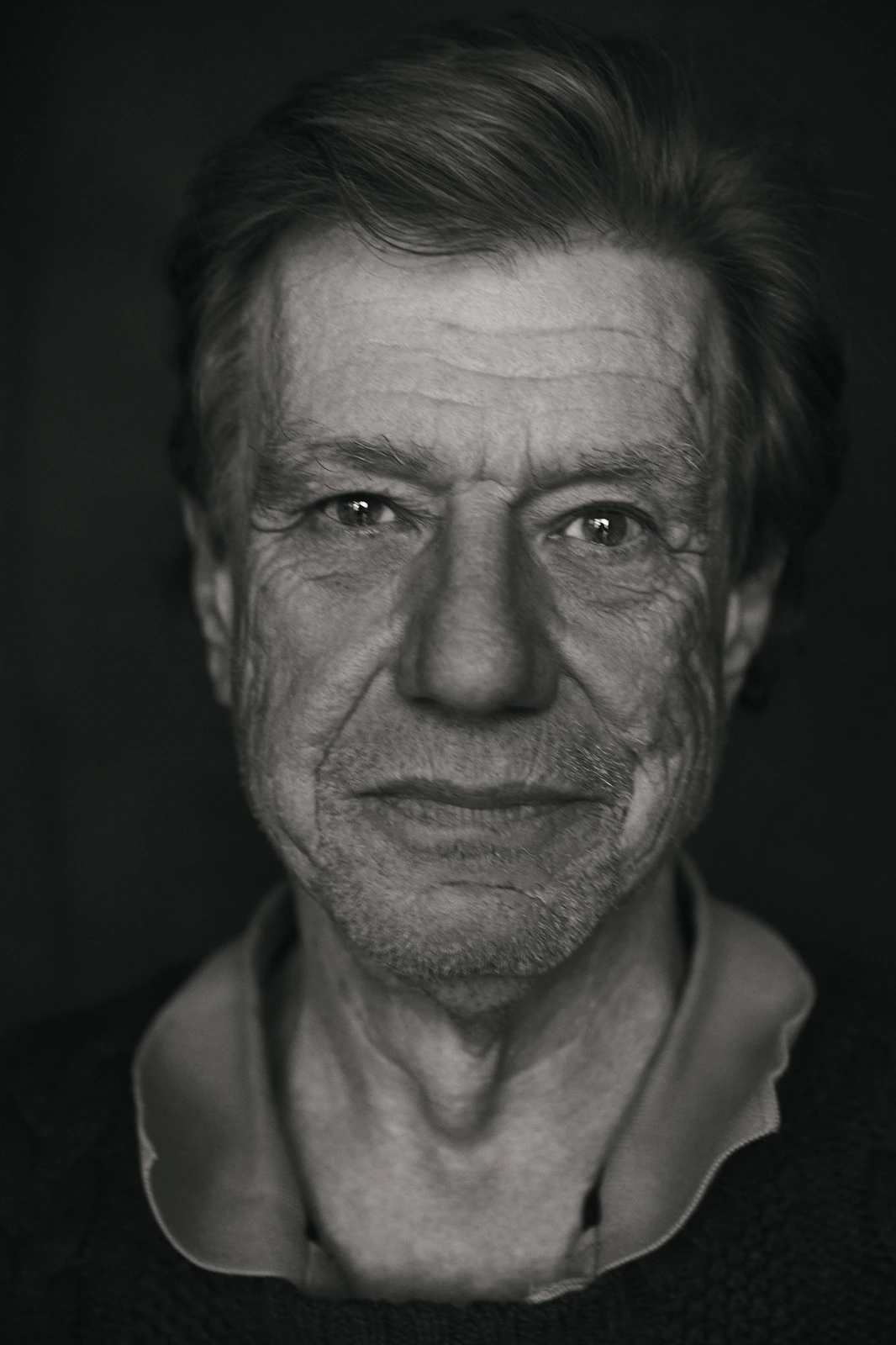 Director John McTiernan of Die Hard, intense gaze direct to camera in a stark black-and-white close portrait against deep.