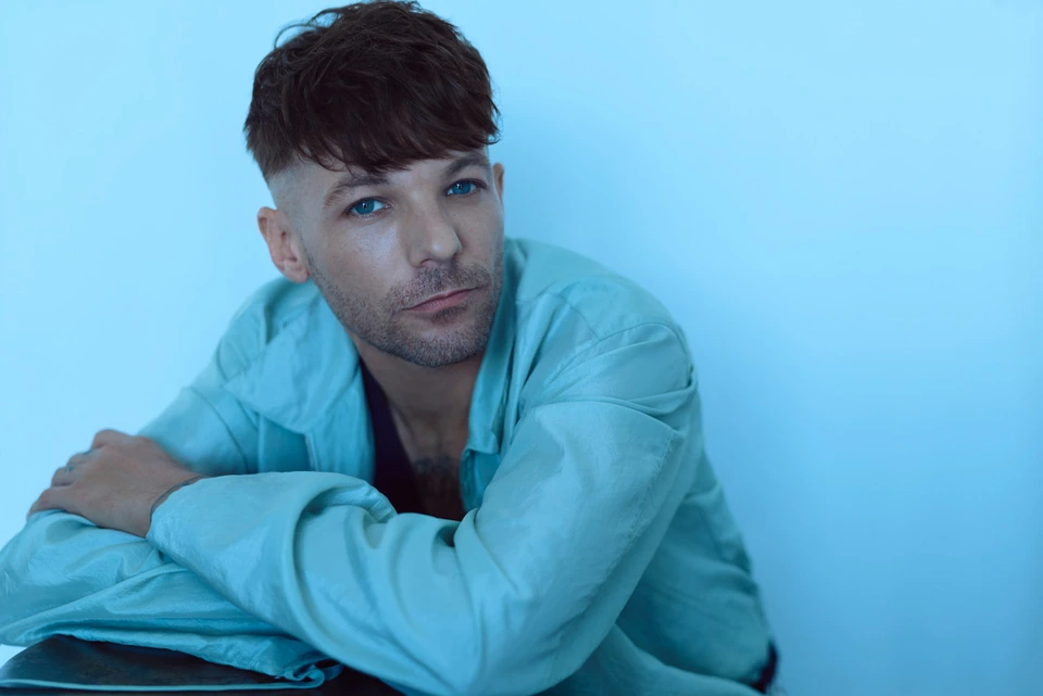 Singer-songwriter Louis Tomlinson, , arms crossed in a pale blue jacket, cool cyan light, photo by Austin Hargrave