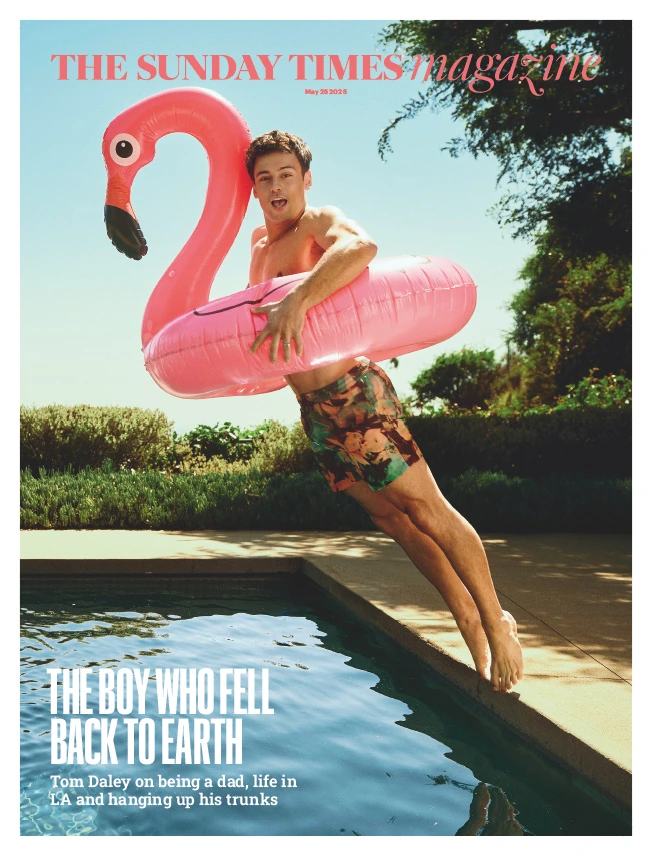 Olympic diver Tom Daley mid-leap poolside, grinning behind a giant pink flamingo float in floral trunks, for The Sunday.