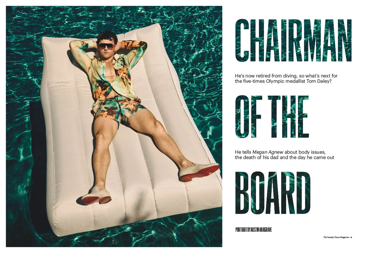 Olympic diver Tom Daley reclined on a pool float in a floral shirt and shorts, sunglasses on, turquoise water beneath.