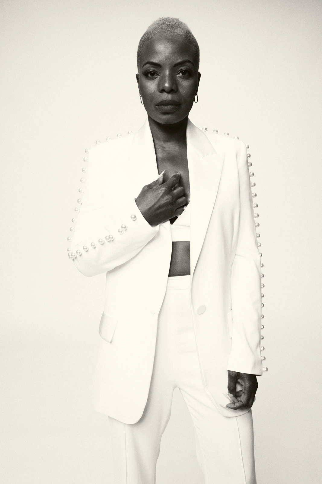 Actor Marsha Stephanie Blake in a pearl-studded white blazer, cropped top and wide-leg trousers, gaze steel-cool against.