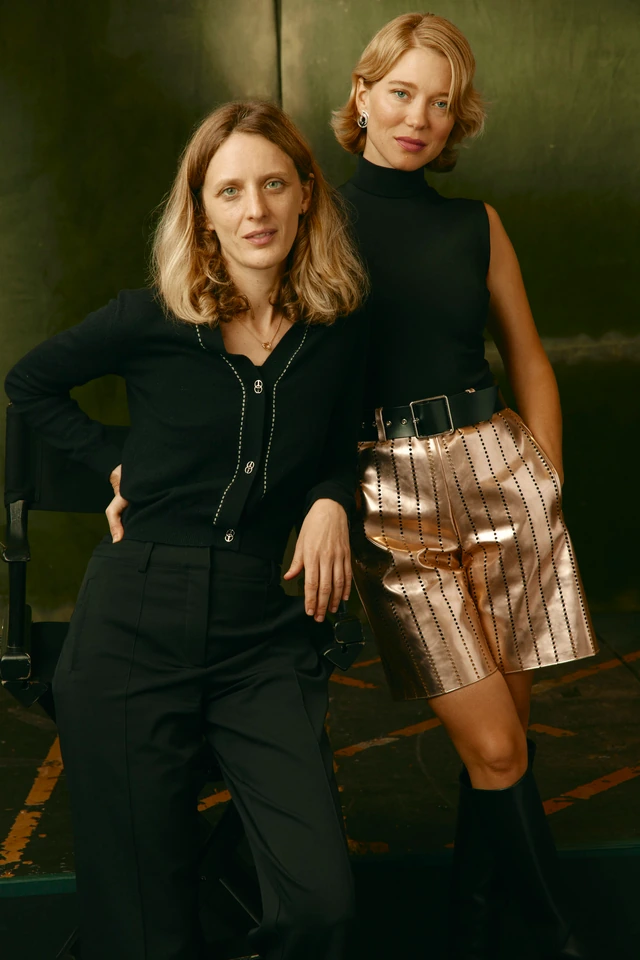 Director Mia Hansen-Løve and actress Léa Seydoux in black against a deep olive backdrop, metallic copper skirt catching.