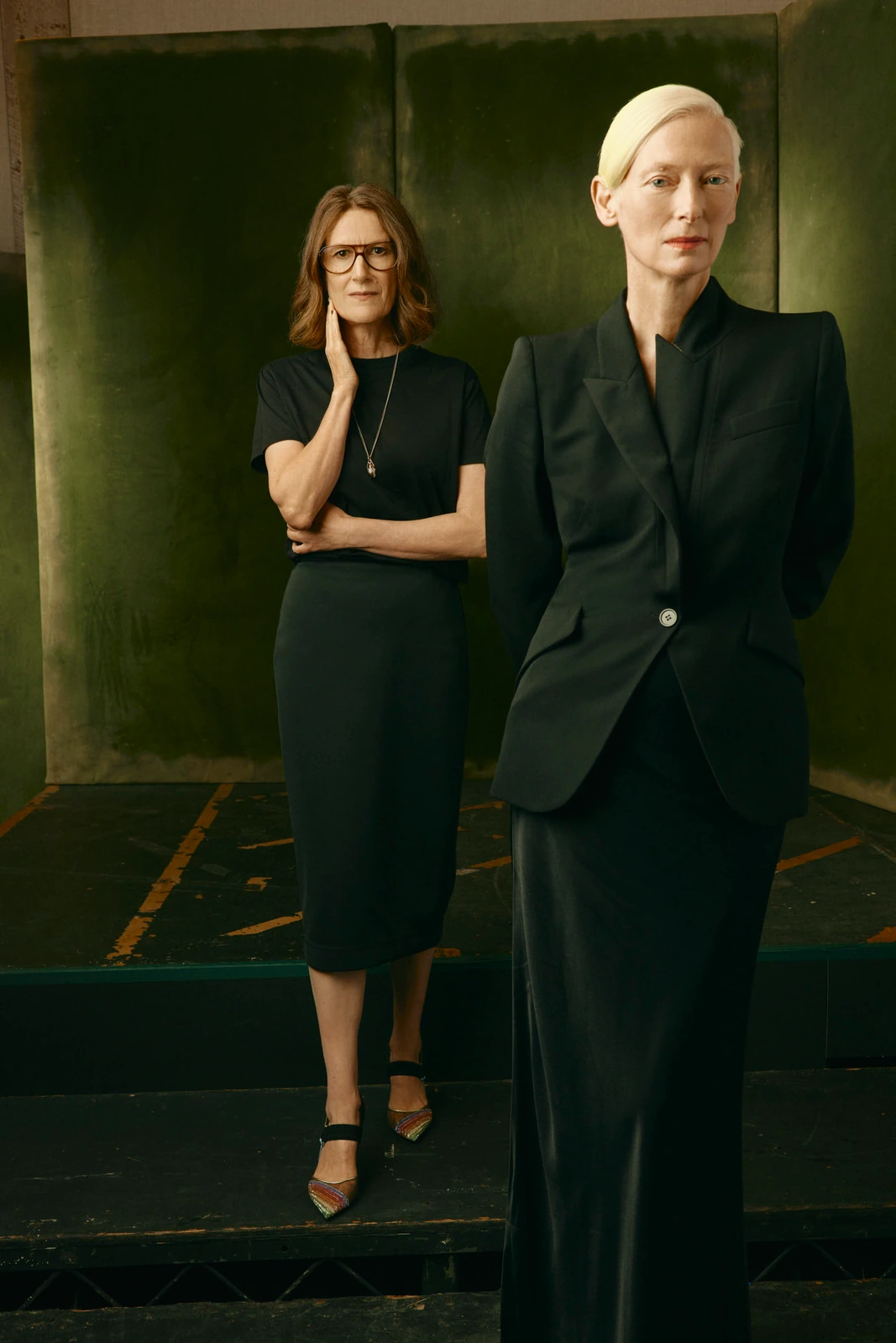 Director Joanna Hogg and actor Tilda Swinton in all-black against deep olive panels, Toronto Film Festival 2022, by Austin.